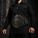 Person wearing a black championship belt against a dark background