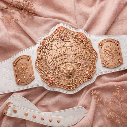 White championship belt with gold medallion on a pink fabric background